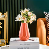 Vaso geométrico laranja com flores claras sobre livros, junto a uma poltrona