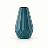 Vaso azul-petróleo com corpo alongado e relevos geométricos sobre fundo claro