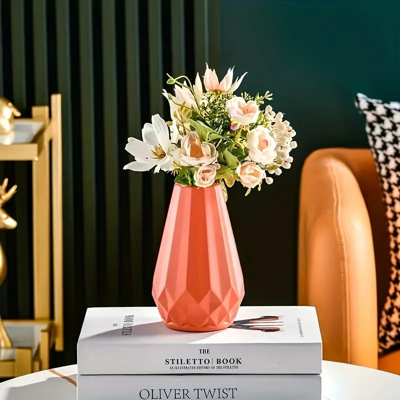Vaso geométrico laranja com flores claras sobre livros, junto a uma poltrona